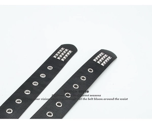 Close-up of black punk belt featuring silver metal eyelets and square pyramid studs