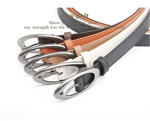 Detail view of five assorted color faux leather skinny belts with oval alloy pin buckles