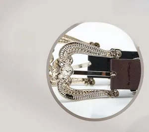 Close-up of vintage crown alloy pin buckle with engraved details on a leather belt