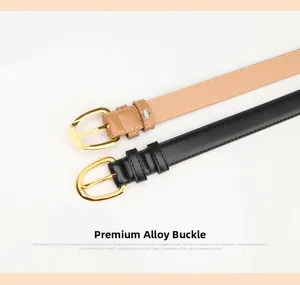 Detail view of two minimalist leather belts in black and tan with gold pin buckles