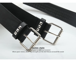 Detail of black leather belt featuring silver square buckle and pyramid stud accents