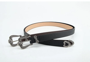 Close-up of vintage engraved silver buckle and metal hardware on black leather belt
