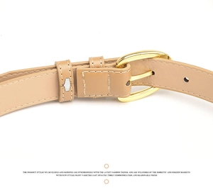 Detail of light brown slim leather belt with oval gold buckle and contrast stitching
