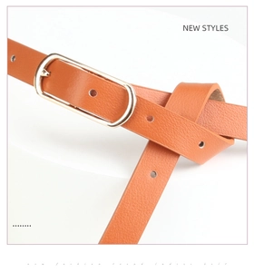 Détail d'une ceinture en cuir marron caramel avec boucle dorée ovale et texture