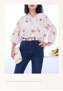 Detailansicht eines cremefarbenen Ledergürtels mit goldener Kettenschnalle auf Jeans