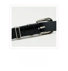 Détail d'une ceinture fine noire montrant la boucle en alliage argenté et le cuir brillant