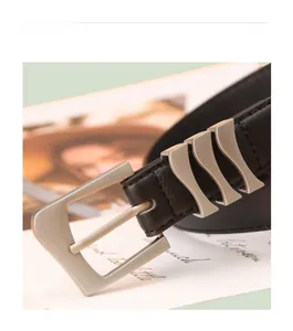 Gros plan d'une ceinture en cuir noir avec boucle carrée argent mat et détails ondulés