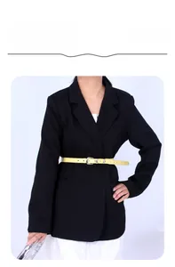 Ceinture fine jaune vif avec boucle argentée portée sur un blazer noir élégant