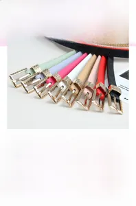 Close-up of colorful women's thin leather belts with luxury gold wavy metal buckles