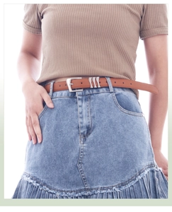 Gros plan d'une ceinture fine en cuir marron clair avec boucle sur jupe en jean