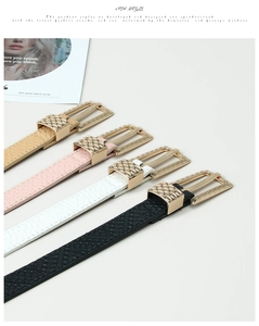 Flat lay of four leather belts in black, white, pink, and tan with gold buckles