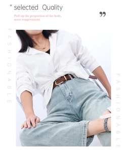 Close-up of a brown leather belt with bamboo buckle on white shirt and blue jeans