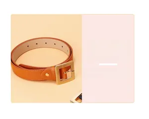 Detail view of caramel brown belt with a bright golden square buckle and fine stitching