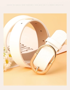Detailed macro view of white PU leather belt with round gold-plated buckle and floral props