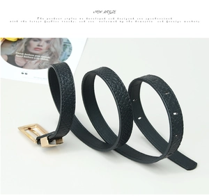 Detail of black pebbled leather belt with a polished gold rectangular buckle on magazine