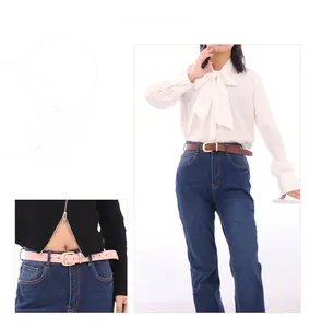 Ceintures femme en similicuir marron et rose avec boucles ardillon dorées sur jean