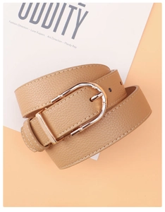 Detailed view of the bright gold horseshoe buckle on camel pebbled leather belt