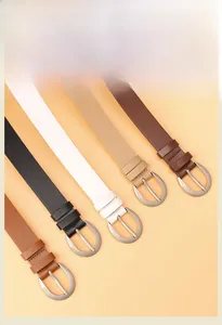 Dettaglio di cinque cinture sottili da donna con fibbie a D argentate su sfondo beige