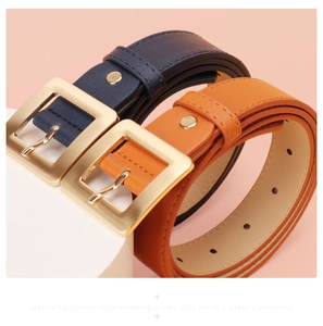 Detail of navy blue and orange leather belts with large square gold buckles for women