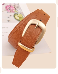 Détail de la ceinture en cuir marron grainé avec boucle ardillon dorée mate et coutures fines