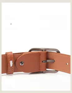 Detailed close-up of brown leather belt featuring grey metal pin buckle and stitching