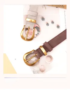 Detail view of retro gray and coffee slim leather belts with vintage gold oval buckles