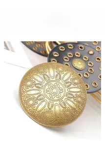 Gros plan sur la boucle de ceinture vintage avec motifs soleil en bronze et rivets