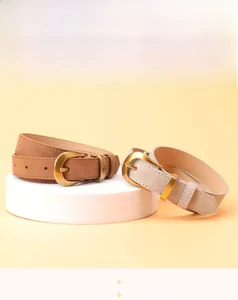 Detail view of stylish tan and beige faux leather belts with oval gold buckles