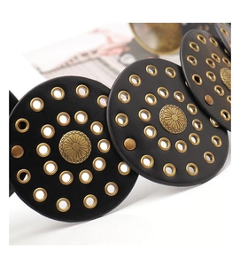 Détail de ceinture vintage Y2K avec cercles en cuir noir et œillets en métal doré