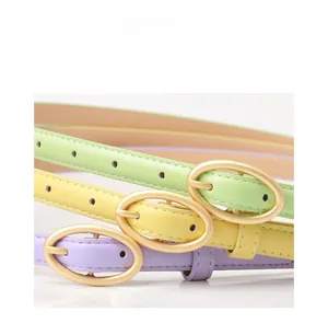 Close-up of pastel skinny belts with matte oval gold buckles in mint, yellow and lilac