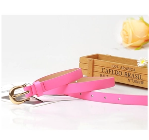 Détail d'une ceinture en cuir PU rose vif avec boucle dorée ronde sur fond bois