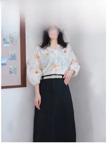 Close-up of a slim beige leather belt styling a floral shirt and high-waisted black skirt