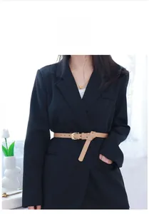 Ceinture fine en cuir PU camel sur un blazer noir avec une boucle dorée ovale élégante