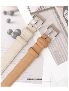 Detail of minimalist leather belts in beige and brown with silver metal buckles