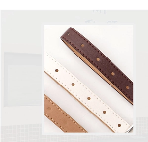 Detail view of stitched faux leather belts in brown and white with polished metal buckle