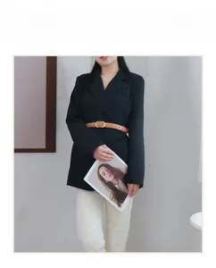 Brown slim leather belt with golden oval buckle shown on black blazer and white pants