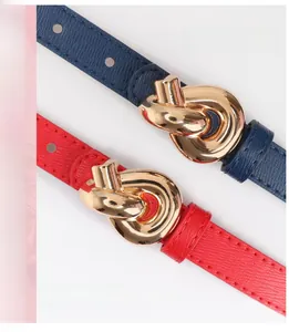 Detail of slim leather belts with gold knot buckles in navy blue and bright red colors