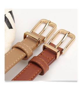 Detailed macro view of thin leather belt with lychee texture and gold rectangular buckle
