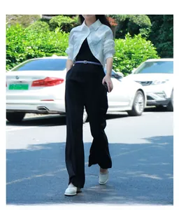 Close-up of a slim purple leather belt styled on a black jumpsuit and white shirt outfit