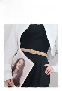 Detail of slim beige leather belt with gold oval buckle on white shirt and black skirt