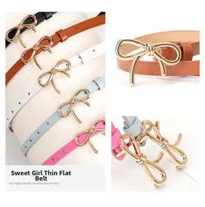 Dettaglio di cinture sottili in pelle con fibbie a fiocco dorato in nero, marrone, bianco e rosa