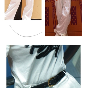 Détail d'une fine ceinture en cuir noir avec boucle dorée sur un pantalon large blanc