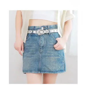 Détail de la ceinture à strass Y2K étincelante portée avec une jupe en jean sur un modèle