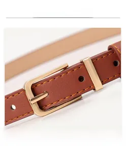Close-up of thin brown leather belt with gold alloy buckle and orange stitching detail