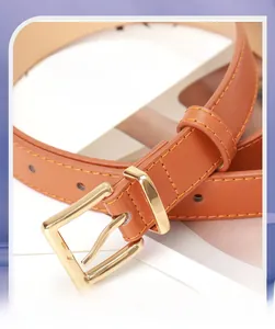 Détail d'une ceinture en cuir marron montrant la boucle dorée et la double couture jaune