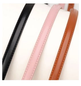 Detail of three slim leather belts in black, pink, and brown with fine stitching detail