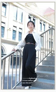 Detailansicht eines braunen Ledergürtels auf schwarzem Jumpsuit und weißem Cardigan