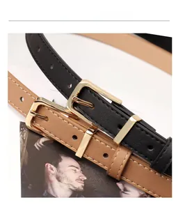 Detail of slim black and brown faux leather belts with gold rectangular buckles and stitching