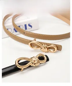 Detail of elegant gold bow metal buckle on black and khaki leather skinny belts