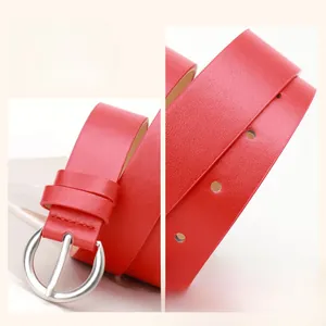 Detail of red leather belt featuring a round silver buckle and fine grain texture